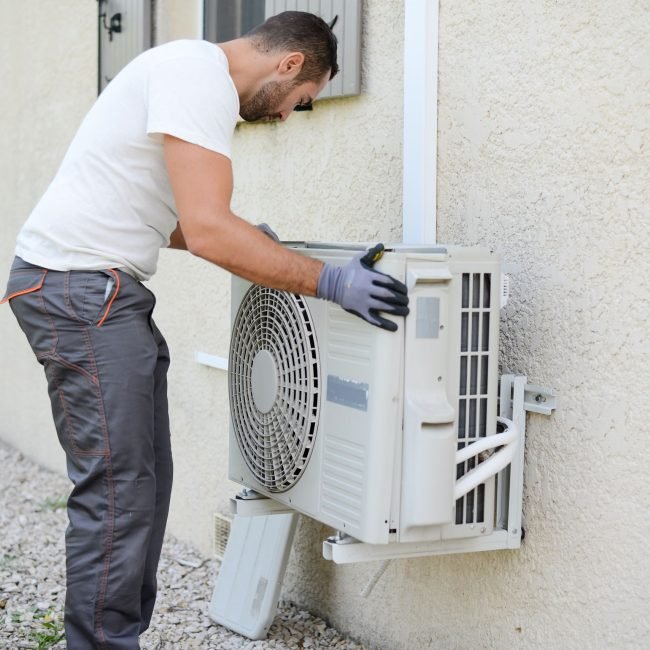 handsome young man electrician installing an air conditioning in a client house